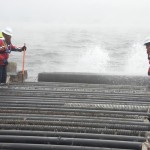 Travis Johnson (left) and Ron Barnes (right), both Naval Support Activity Panama City (NSA PC) Public Works Department (PWD) employees, remove a safety block prior to offloading concrete pilings at sea Jan. 30, 2014. PWD supported a Bay County Florida and Naval Surface Warfare Center Panama City Division (NSWC PCD) initiative to create an artificial in the Gulf of Mexico waters miles off the coast of Panama City Beach, Fla. Photo by Ron Newsome, NSWC PCD.