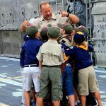 Cub Scout Pack 323 Den Leader, Joe Hajik, receives a congratulatory group hug from Scouts after the announcement of his promotion to Cub Master during the cross-over ceremony onboard Landing Craft Air Cushion (LCAC) 66 June 1, 2015 in Panama City, Florida. (RELEASED) (Photo by Katherine Mapp, NSWC PCD)